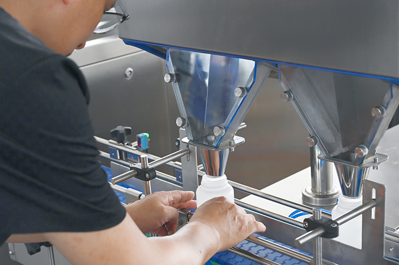 A technician is adjusting the filling nozzle of a tablet counting machine