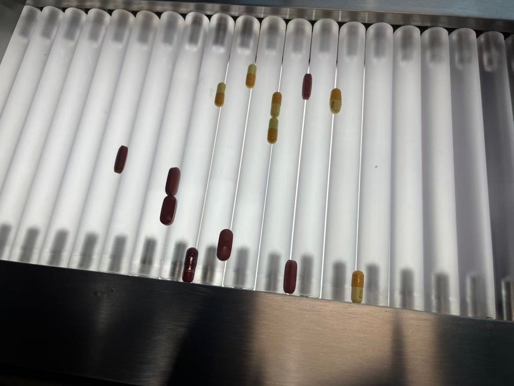 コンベアベルト上の錠剤を手作業で検査する作業員